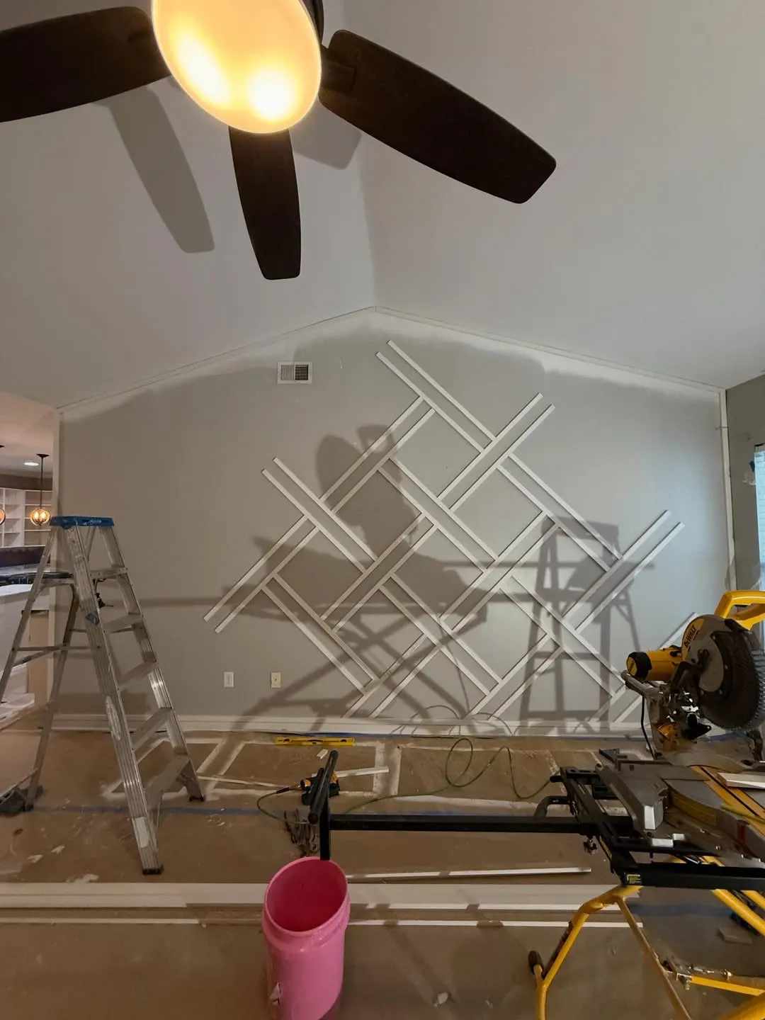 Diagonal trim going up on a wall, with ladder and saw in the room
