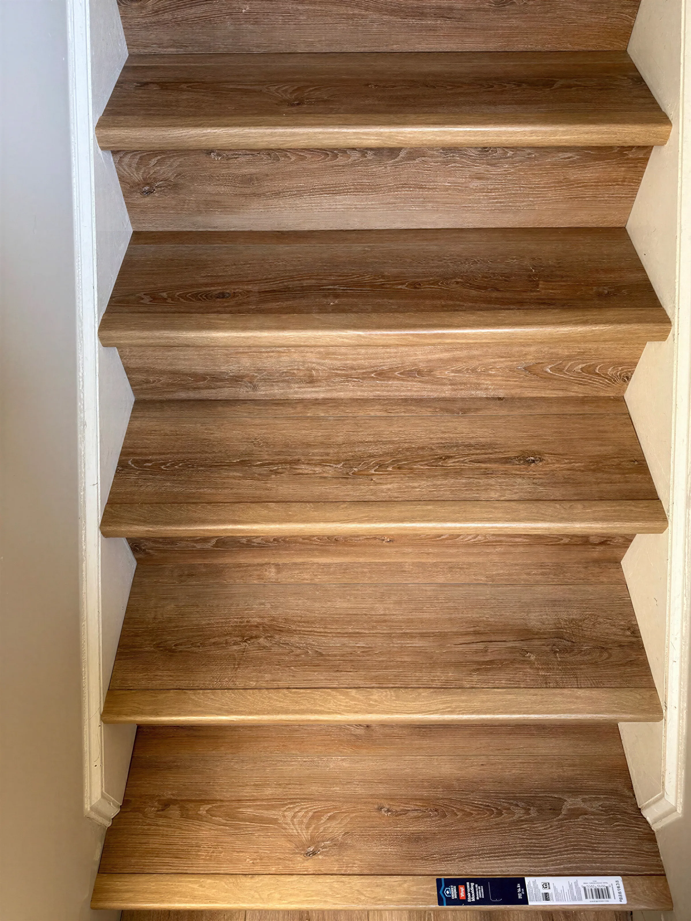 Straight-on view of a staircase finished in oak-look vinyl plank with matching stair nose